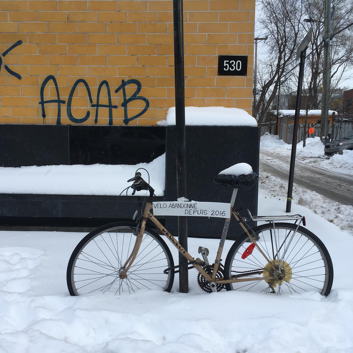 Vélo accroché dans la rue avec une pancarte indiquant vélo abandonné depuis 2016